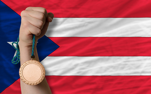 Holding bronze medal for sport and national flag of puertorico