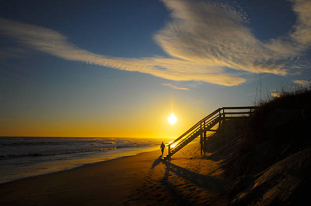 Man walking on beach at sunset stock photo