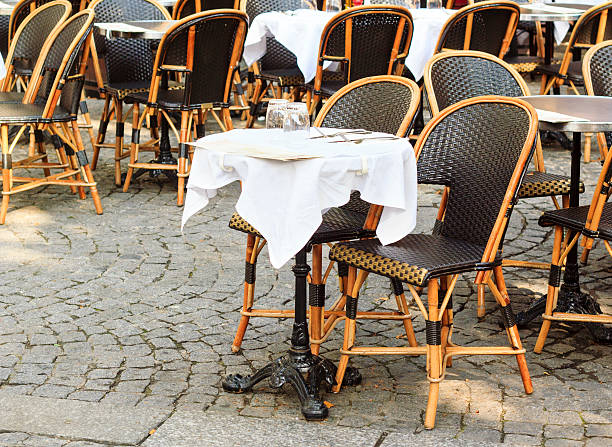 Open street Cafe in Paris - traditional wicker furniture and dressed for lunch tables exposed on the pavement, Paris, France
