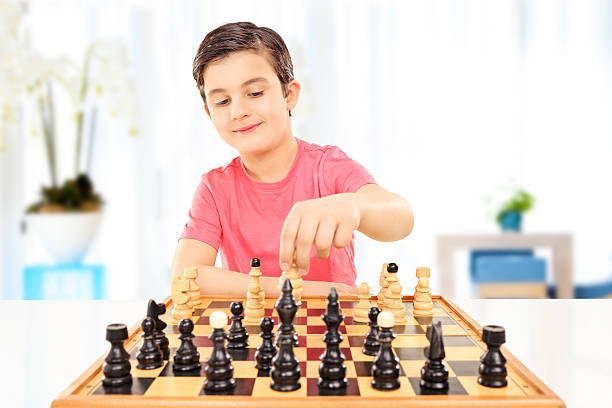 istock Little boy playing chess seated on a table 478772213