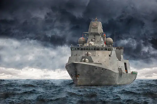 The military ship on sea against heavy clouds.