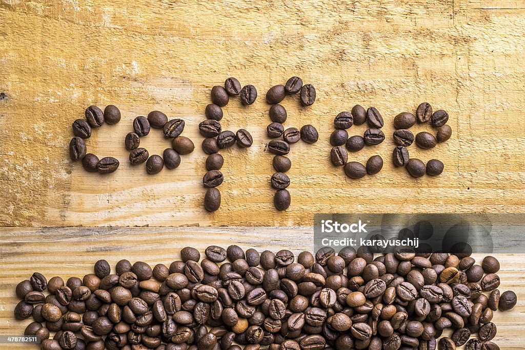 Coffee Beans and Wood Light wood background texture with coffee beans writing the word "coffee" Black Color Stock Photo