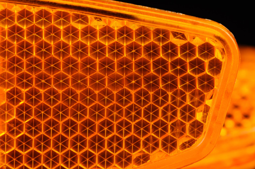 A macro shot of an orange bicycle retroreflector