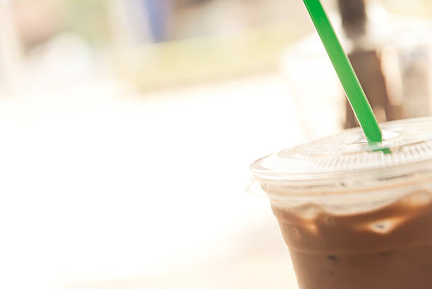 Plastic glass of ice mocha coffee with green straw closeup creamy tone like instagram filter