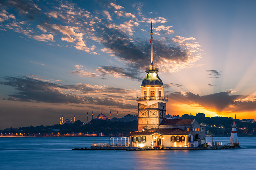 Maiden's Tower lit up in early evening, with the Hagia Sophia and the Blue Mosque in the far distance.