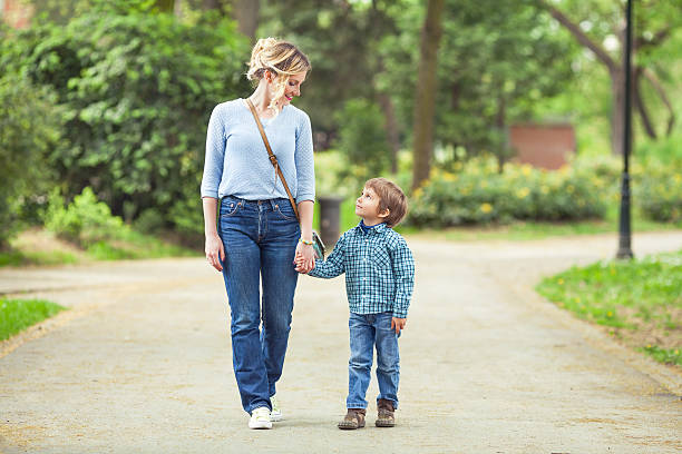 Mother and Son in a Park Young mother and her cute little son walking in a park kids holding hands stock pictures, royalty-free photos & images