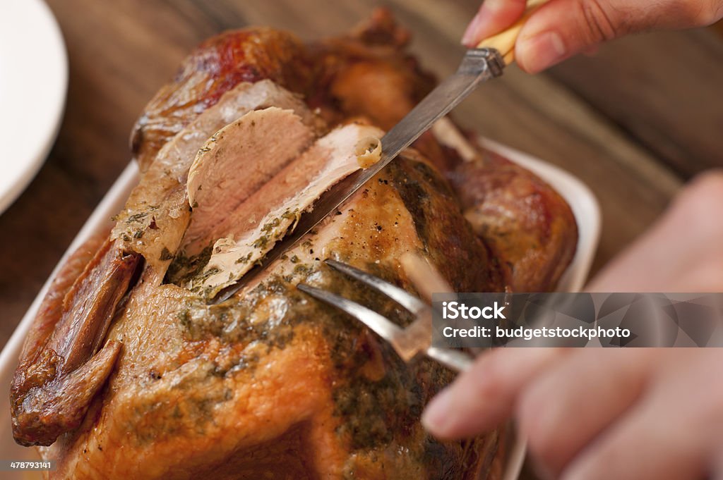 Carving a tasty Thanksgiving roast turkey Closeup view from above of a man carving a tasty Thanksgiving roast turkey slicing the breast with a carving knife Carving - Craft Activity Stock Photo