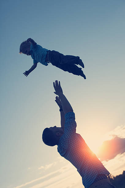 istock silhouette of father throwing and catching his son 478798190