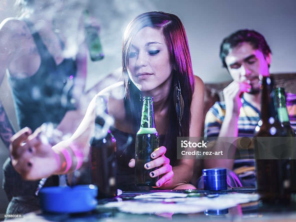 girl putting joint in ashtray at crazy party photo of a girl putting joint in ashtray at crazy party with smoke in the air. Teenager Stock Photo