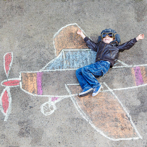 istock Little boy having fun with airplane picture drawing with chalk 478803406