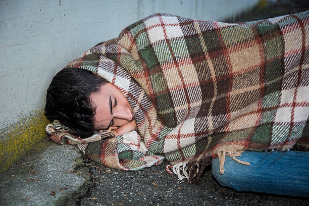istock Young male beggar on city sidewalk sleeping 478803834