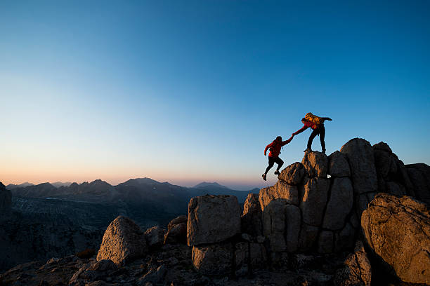 climbing to the top One climber helping the other get to the top of a mountain unyielding stock pictures, royalty-free photos & images