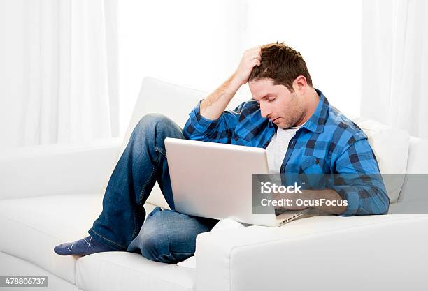 Worried Attractive Man With Computer Sitting On Couch Stock Photo - Download Image Now