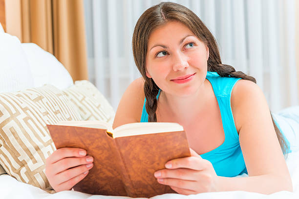 istock attractive young girl with an interesting novel in bed 478810740