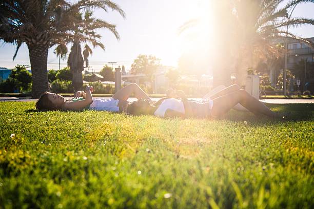 Teenagers relaxing laying on the grass at the park Teenagers relaxing laying on the grass at the park they are laughing and talking togethers. hot filipina women stock pictures, royalty-free photos & images