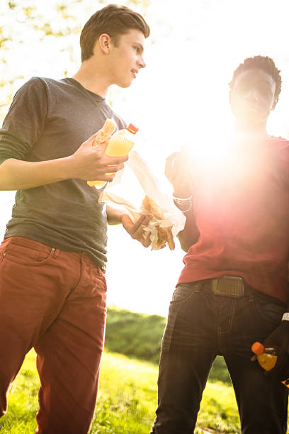 Selective focus of small group of unrecognizable young friends getting bottle so beer and cocktails from a cooler to enjoy during their picnic in the nature.
