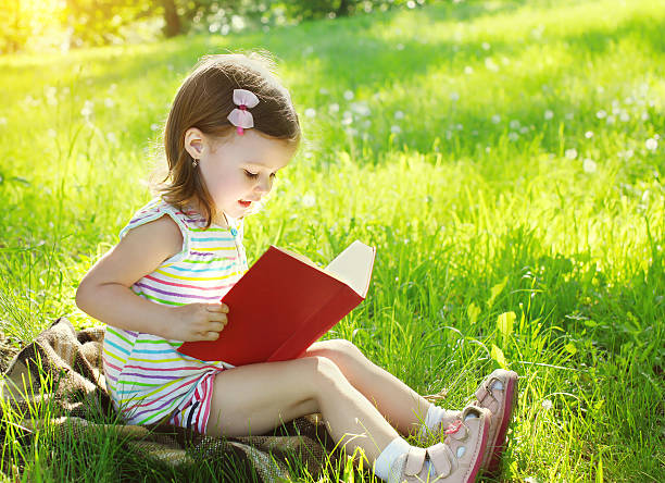 istock Child reading a book on the grass in sunny summer 478815456