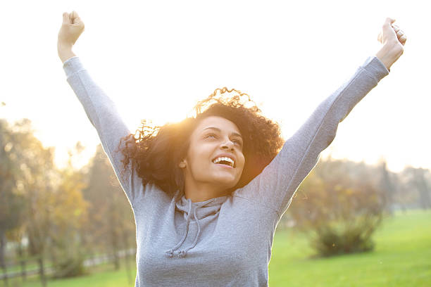 istock Cheerful young woman smiling with arms raised 478821060
