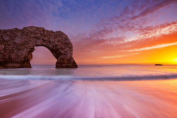Durdle Door rock arch in Southern England at sunset The Durdle Door rock arch on the Dorset Coast of Southern England at sunset. durdle door stock pictures, royalty-free photos & images