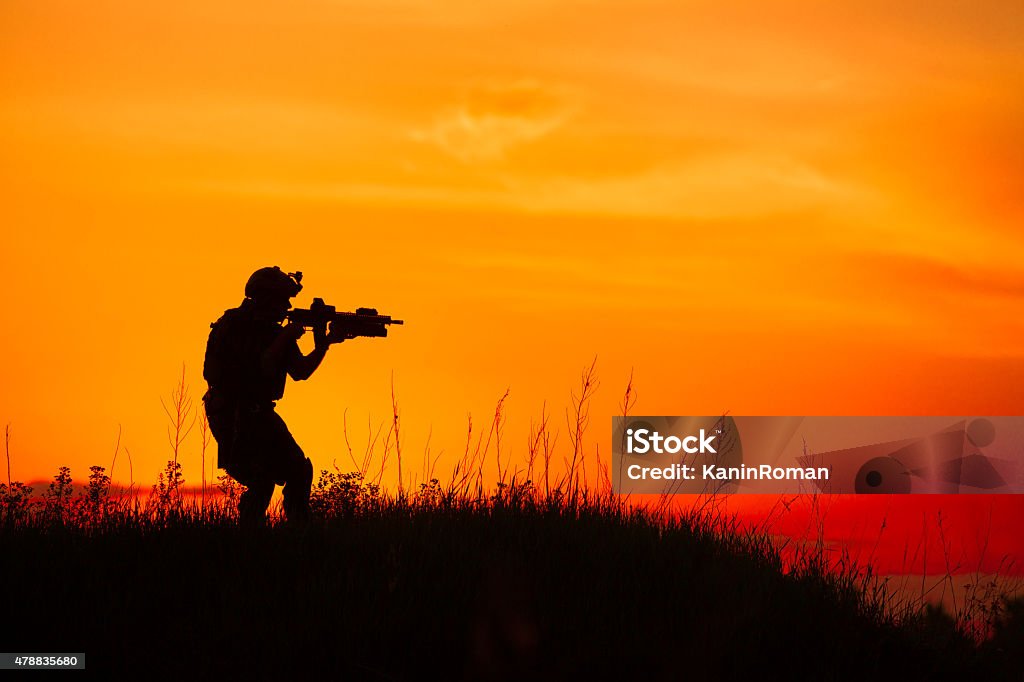 Silhouette of military soldier or officer with weapons at sunset Silhouette of military soldier or officer with weapons at sunset. shot, holding gun, colorful sky, background 2015 Stock Photo