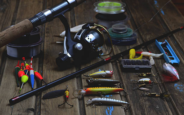 Fishing tackle - fishing rod, fishing line, hooks and lures Fishing tackle - fishing rod, fishing line, hooks and lures on wooden background minnow fish photos stock pictures, royalty-free photos & images