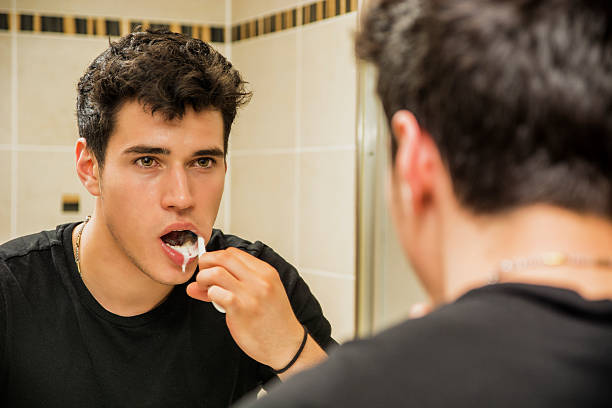 photo de séduisante jeune homme se brosser les dents - smiling human teeth toothbrush moving up photos et images de collection