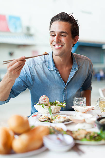 tourist mann essen asiatische essensstraße lokale café, lächeln - eating men food chopsticks stock-fotos und bilder