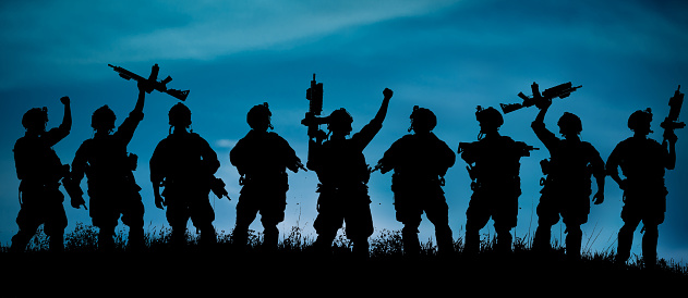 Silhouette of military soldiers team or officer with weapons at night. shot, holding gun, blue colorful sky, background