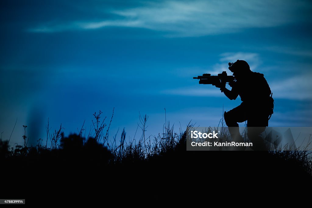 Silhouette of military soldier or officer with weapons at night. Silhouette of military soldier or officer with weapons at night. shot, holding gun, blue colorful sky, background 2015 Stock Photo