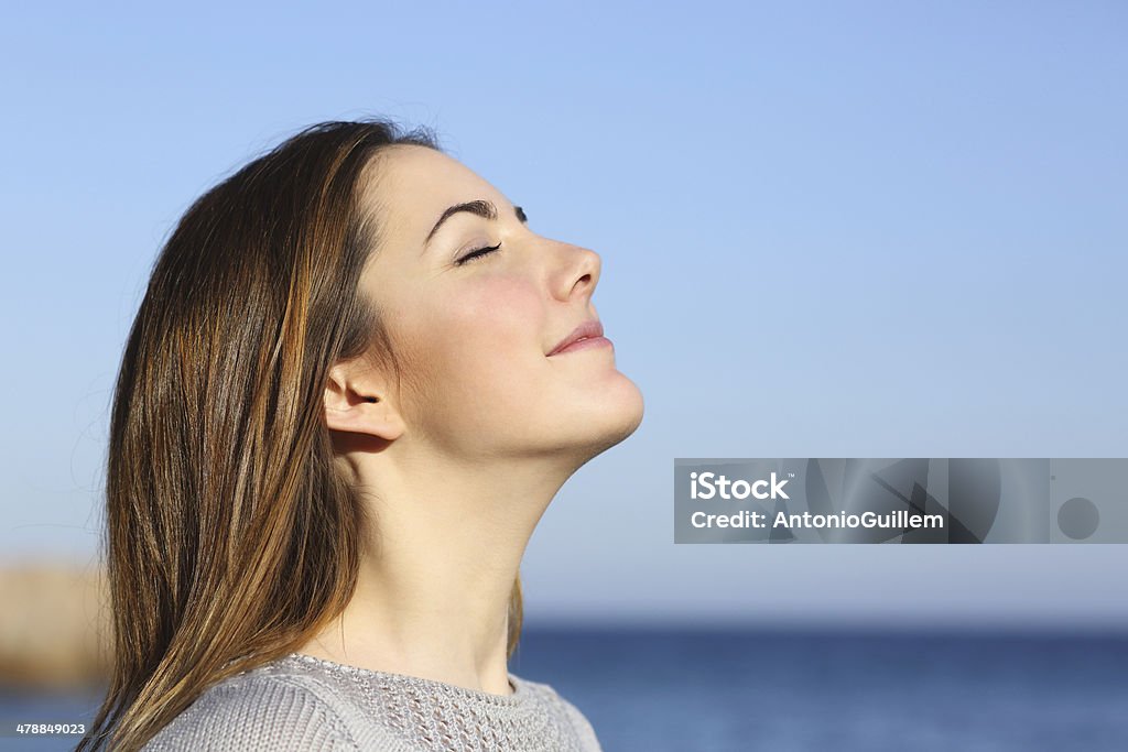 Woman portrait breathing deep fresh air on the beach Woman profile portrait breathing deep fresh air on the beach with the ocean in the background Breathing Exercise Stock Photo