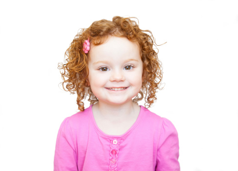 Cute little girl with curly red hair on a white background.