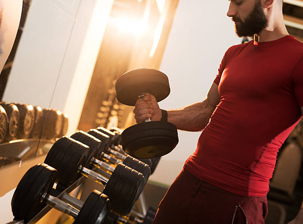 istock Muscular build man taking dumbbells in a gym. 478864344