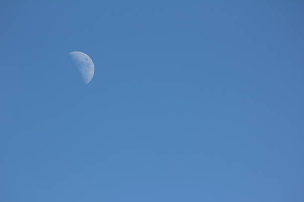 White moon shines in the clear blue sky.