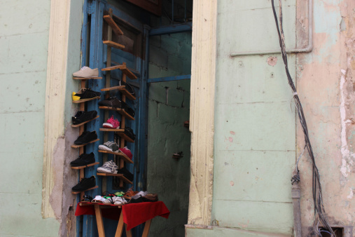 Interesting photo of a unique shoe store in a small doorway in an old dilapidated building in Havana, Cuba.