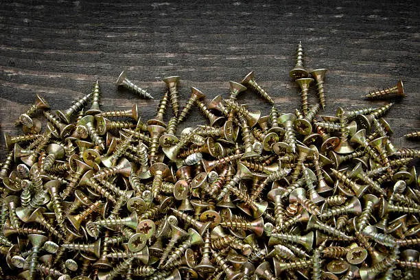 Many screws lying on a wooden board