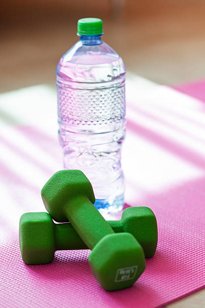 istock Two dumbbells with mineral water on yoga mat 478881914