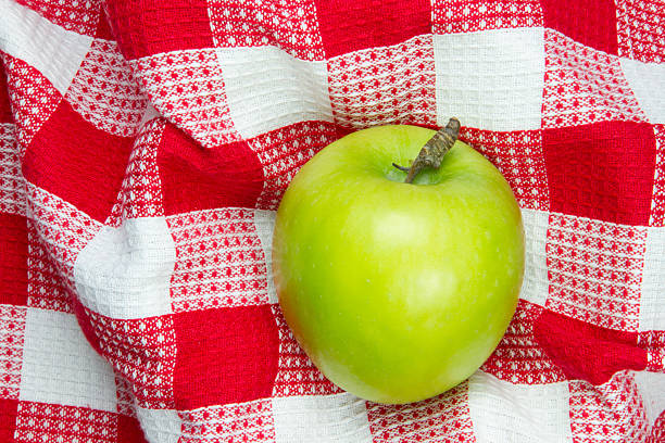 red and white checkered table cloth with green apple on it