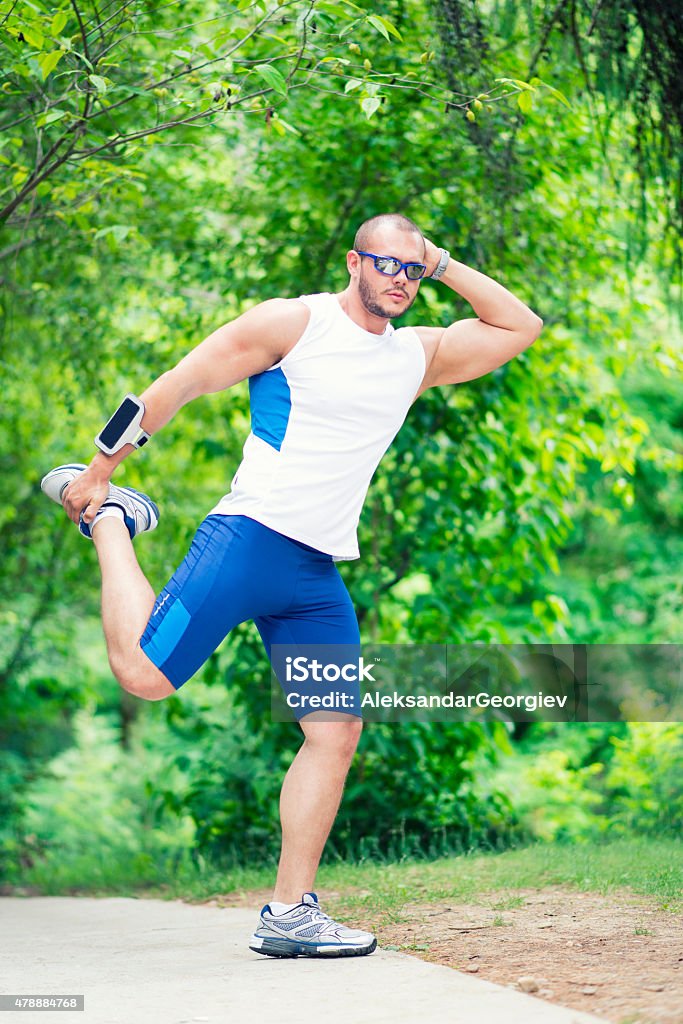Muscular Male Stretching in Nature and Ready to Work out Muscular Male Stretching in Nature and ready to work out running. Wearing summer running clothing, sunglasses, watch and GPS locator 20-29 Years Stock Photo