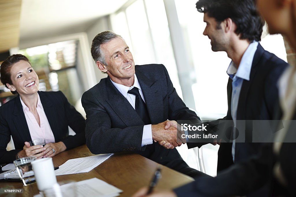 Pleased to do business with you A group of professional businesspeople in a meeting and concluding a deal with a handshake 20-29 Years Stock Photo