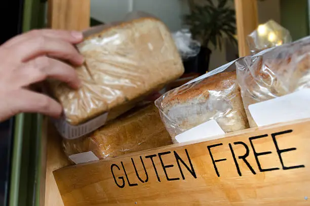 A woman hand picks up a Gluten Free loaf of bread.