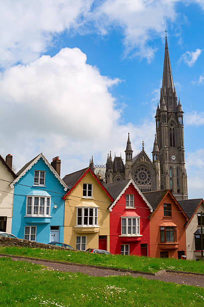 Colorful Houses on Street in Cobh, Ireland A row of colorful houses. known locally as the deck of cards.  These houses are on a steep hill near the waterfront in Cobh.  In the background is the St. Colman's Cathedral.  Image taken from a small park across Westview Street from the row houses in late spring. county cork stock pictures, royalty-free photos & images