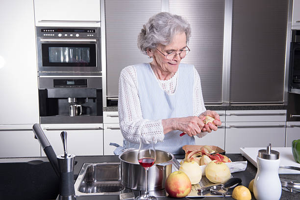aktywna kobieta starszy obieranie jabłka w kuchni - grandmother pie cooking baking zdjęcia i obrazy z banku zdjęć