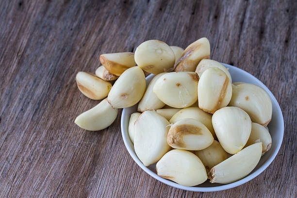 istock Peeled garlic in a cup on a wooden table. 478905844