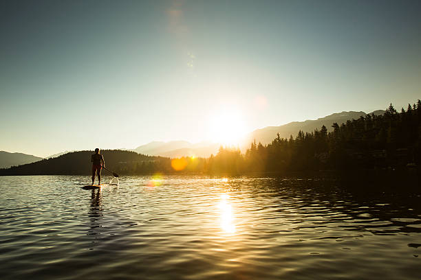 stehpaddeln auf see bei sonnenaufgang oder sonnenuntergang. - whistler britisch kolumbien stock-fotos und bilder