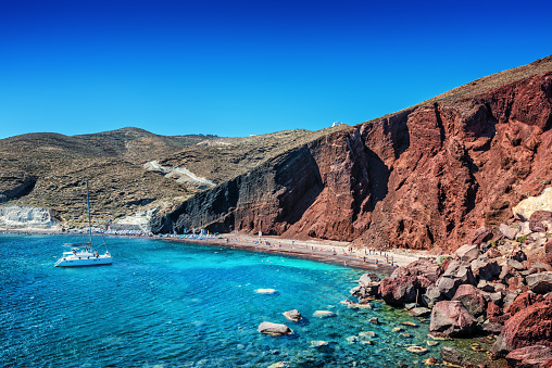 Red Volcanic Beach with on Santorini. Beautiful summer day with clear sky over the Turquoise Water on Santorini, Greece.