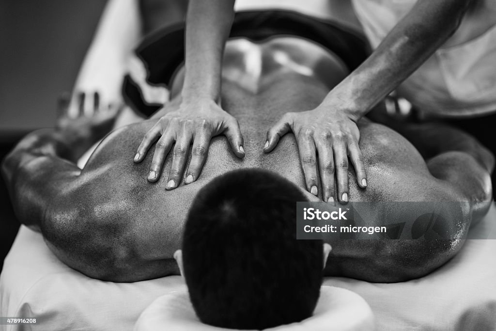 Sports massage - Shoulders Sports massage - Shoulder massage - Physical therapist doing massage of shoulders. Black and white photo, selective focus. Massaging Stock Photo