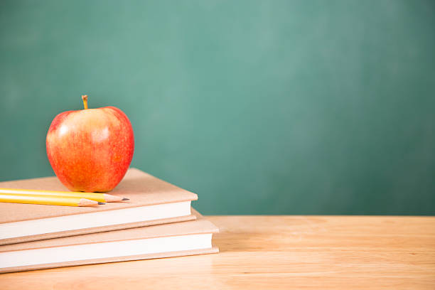 istock Back to school. Textbooks, apple, pencils on desk. Chalkboard. 478916270