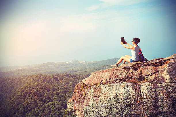 istock woman hiker use digital tablet at mountain peak cliff 478921808