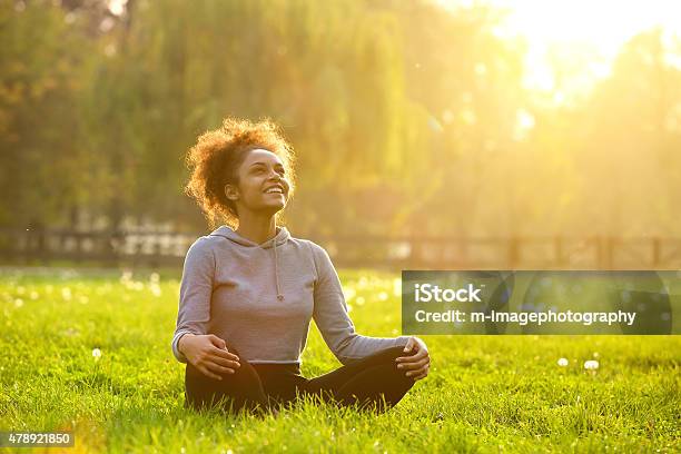 Felice Giovane Donna Seduta In Una Posizione Yoga - Fotografie stock e altre immagini di Salute - Salute, Natura, Donne
