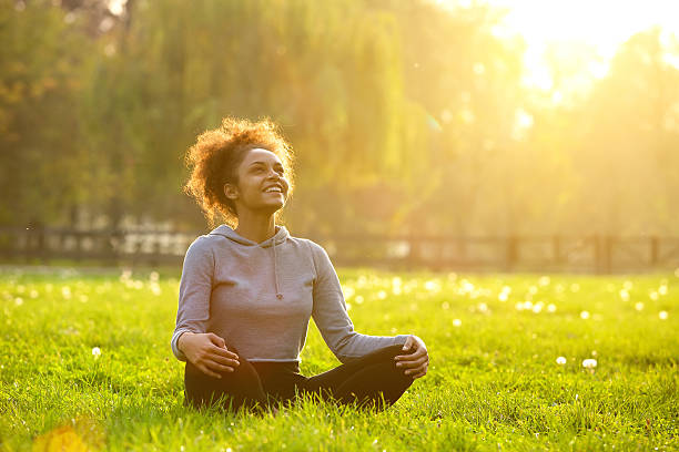 Happy young woman sitting in yoga position Happy young woman sitting outdoors in yoga position looking up photos stock pictures, royalty-free photos & images